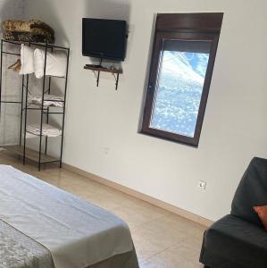 um quarto com uma janela, um sofá e uma televisão em Terriña Salvaxe em Quiroga