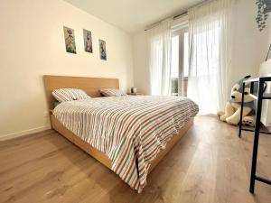 um quarto com uma cama com um urso de peluche ao lado de uma janela em Le cocon marnais - appart 2P em Villiers-sur-Marne