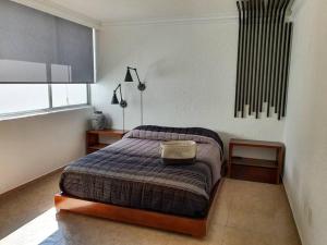 a bedroom with a bed and two tables and a window at Hermoso departamento con excelente ubicación in San Luis Potosí