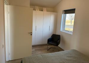 a bedroom with a black chair and a window at Farmer's Guest House in Hella