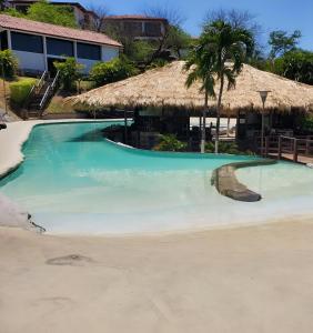 a large swimming pool with a thatch roof at Casa de Encanto Tropical Villa in Playa Hermosa
