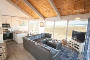 a living room with a leather couch and a television at Ocean Front...Sand in your toes getaway!! in Pacific City