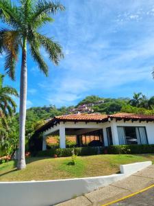 a house with a palm tree in front of it at Casa de Encanto Tropical Villa in Playa Hermosa