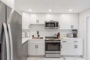 a kitchen with white cabinets and a stainless steel refrigerator at Villa at St James Unit A Luxury Pool Villa, Pet Friendly in Miami
