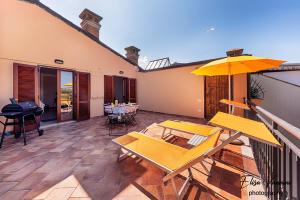 un patio con mesas y una sombrilla en el balcón en Terrazza Sulla Luna en Casciana Terme