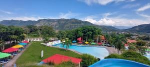 una piscina en un complejo con montañas en el fondo en Hotel y Parque Acuatico Agua Sol Alegria en Honda