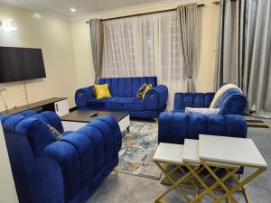 uma sala de estar com sofás azuis e uma televisão de ecrã plano em Elysian Homes em Nakuru