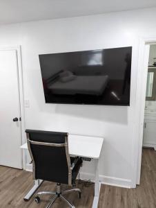 a desk with a chair and a large television on a wall at Newly Renovated Studio - Close to WakeMed Raleigh in Raleigh