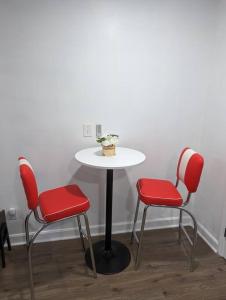 a table with two red chairs and a white table with a table at Newly Renovated Studio - Close to WakeMed Raleigh in Raleigh