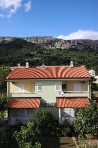 una casa con techo naranja con una montaña al fondo en Mediterranean Oasis Apartments en Baška