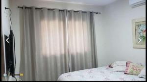 a bedroom with a bed and a window with curtains at Maravilha em Tibau do Sul in Tibau do Sul