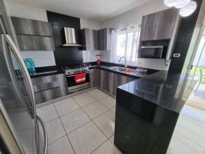 a kitchen with black cabinets and a stove top oven at Palmeira71, acogedora Casa en Privada de ValleAlto in Bellavista