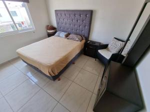 a small bedroom with a bed and a chair at Palmeira71, acogedora Casa en Privada de ValleAlto in Bellavista