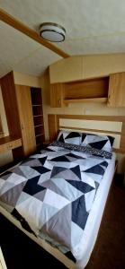 - une chambre avec une couette en noir et blanc sur un lit dans l'établissement 3 bedroom caravan, à Kinmel Bay