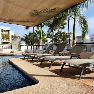 a row of lounge chairs next to a swimming pool at Palmeira71, acogedora Casa en Privada de ValleAlto in Bellavista