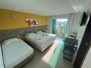 a hotel room with two beds and a table at Pousada Dunas Beach in Canoa Quebrada +26 photos