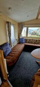 - un grand canapé brun dans une chambre avec fenêtre dans l'établissement 3 bedroom caravan, à Kinmel Bay