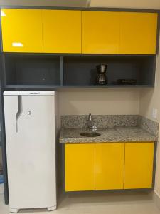 a kitchen with yellow cabinets and a sink at Spazzio Diroma - Hospedagem com Acqua Park (Parque do Vulcão) in Caldas Novas