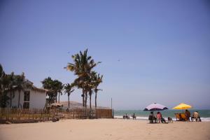 曼科拉的住宿－Casa Tito Máncora - Bungalow Privado，一群人站在海滩上,拿着遮阳伞