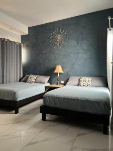 two beds in a bedroom with a blue wall at DEPARTAMENTO CON TERRAZA Y VISTA para 6 personas in Chihuahua