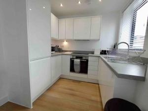een witte keuken met witte kasten en een wastafel bij Luxury 2 Bed 2 Bath Flat Near Old Trafford in Manchester