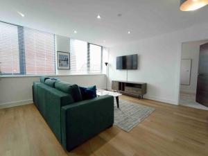 a living room with a green couch and a tv at Luxury 2 Bed 2 Bath Flat Near Old Trafford in Manchester