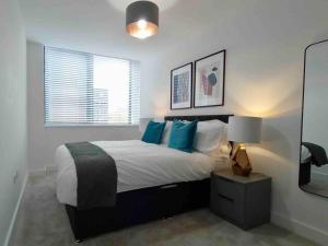 a bedroom with a bed with blue pillows and a mirror at Luxury 2 Bed 2 Bath Flat Near Old Trafford in Manchester