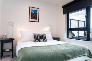 a bedroom with a bed with a green blanket and a window at Wildflower Retreat by Revelstoke Vacations in Revelstoke