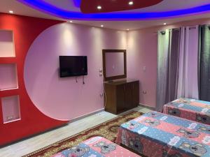 a room with two beds and a flat screen tv at Osama Fwaz in Cairo