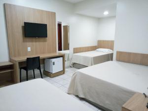 a hotel room with two beds and a television at Tawfiqs Hotel in Barra do Garças