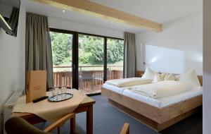 a bedroom with a bed and a table and a window at Gästehaus Rottenspacher in Kössen