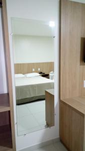 1 dormitorio con cama y espejo en una habitación en Tawfiqs Hotel, en Barra do Garças