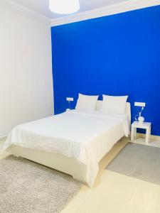 a blue bedroom with a white bed with a blue wall at WELKAM Home & Coworking in Essaouira