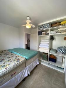 a bedroom with a bed and shelves with towels at Casa em condomínio fechado - Praia de Itaguaré in Bertioga