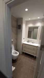 a bathroom with a toilet and a sink and a mirror at First Avenue AVM Residences in Buyukcekmece