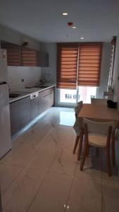 a kitchen with a table and a refrigerator and a table and chairs at First Avenue AVM Residences in Büyükçekmece