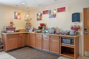 a kitchen with wooden cabinets and a microwave at Best Western Plus Lonoke Hotel in Lonoke