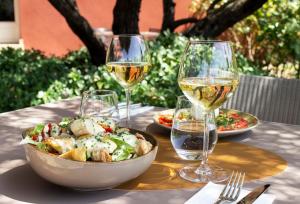 a table with a bowl of salad and two glasses of wine at Best Western Plus Le Lavarin Avignon in Avignon
