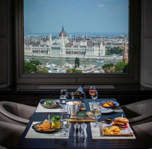 a table with food and wine glasses and a large window at Hilton Budapest in Budapest