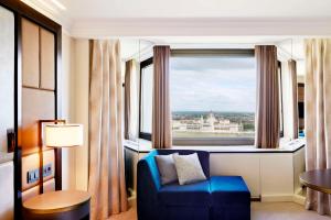 a room with a blue chair and a large window at Hilton Budapest in Budapest