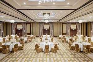 um salão de banquetes com mesas e cadeiras brancas e lustres em Hilton Budapest em Budapeste