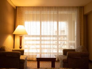 アーメダバードにあるRadisson Blu Hotel Ahmedabadの窓付きのリビングルーム、椅子2脚、テーブルが備わります。