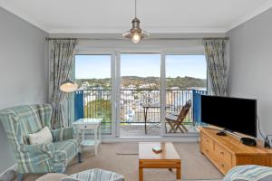 Una sala de estar con televisión y una gran ventana. en Brynawelon - Wonderful Sea and Harbour Views, en Saundersfoot