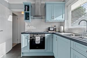 Una cocina con gabinetes azules y un fregadero. en Brynawelon - Wonderful Sea and Harbour Views, en Saundersfoot