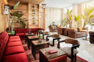 un hall avec des canapés rouges, des tables et des plantes dans l'établissement Avani Avenida Liberdade Lisbon Hotel, à Lisbonne