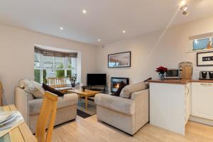 a living room with two couches and a kitchen at Park Place Court - Close to Beach with Parking in Tenby