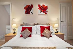 a bedroom with a white bed with red pillows at Park Place Court - Close to Beach with Parking in Tenby