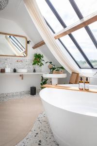 - une salle de bains avec une grande baignoire blanche dans une chambre dotée de fenêtres dans l'établissement LA GRANDE MAISON LGM, à Lesches