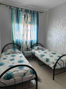 una camera con due letti e una finestra con tende di Beautiful apartment-High speed WIFI-iPTV-Netflix a El Jadida