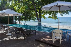 a pool with chairs and umbrellas next to the ocean at Mighil Hotel & Eventos in Florianópolis